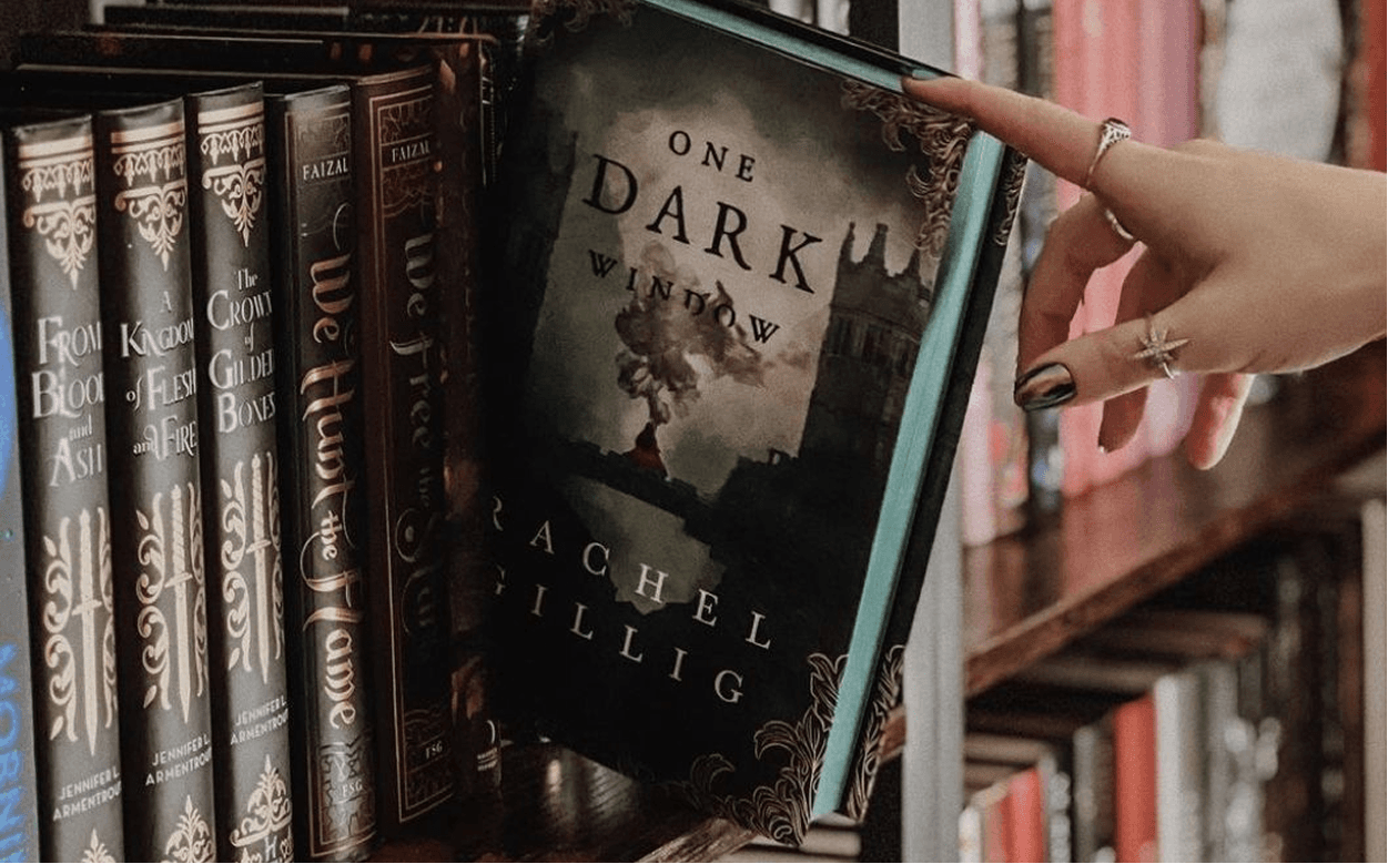 Hand selecting a published book from a bookshelf in a library